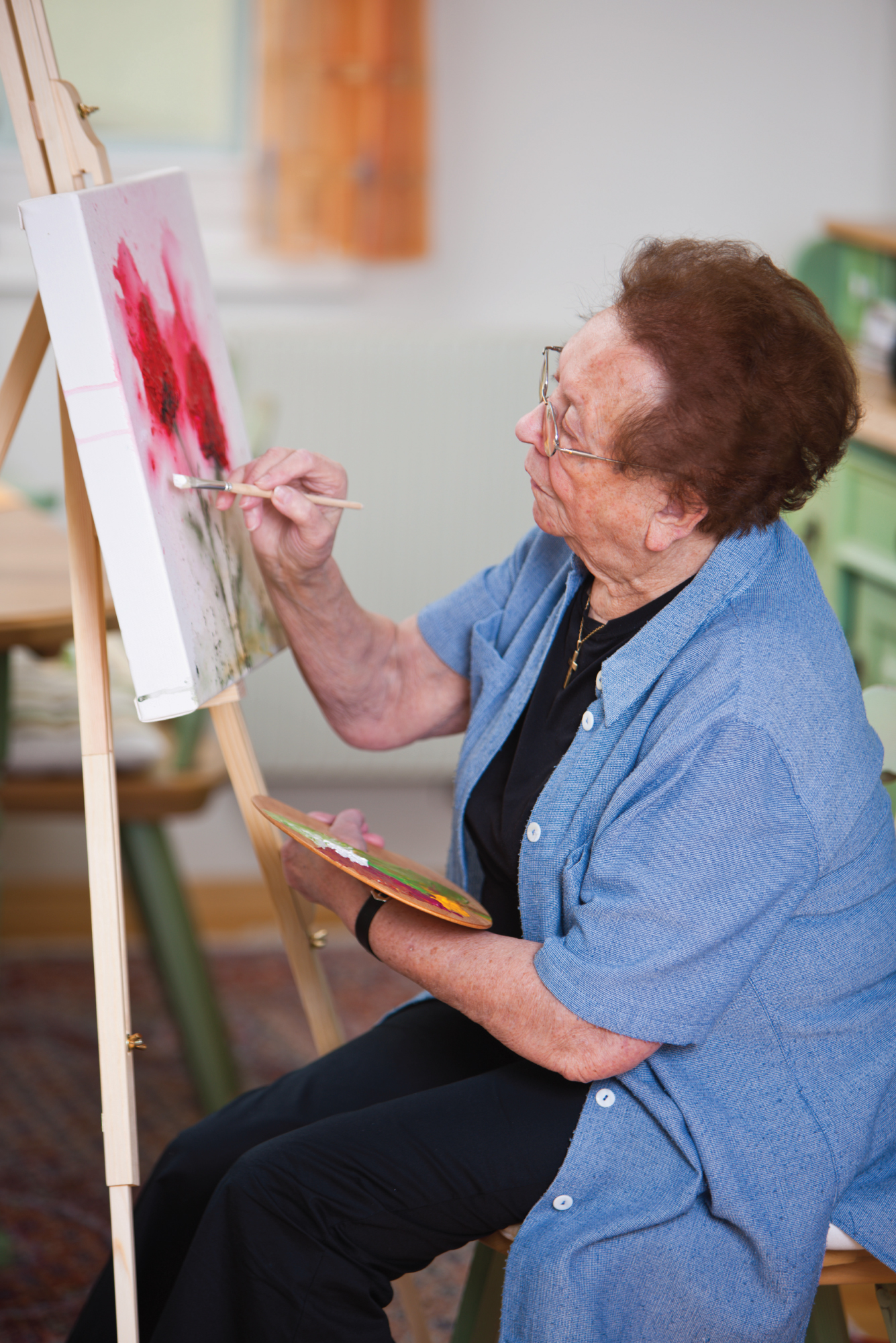 elderly woman painting pink flowers - Maple Care Homes residential assisted living