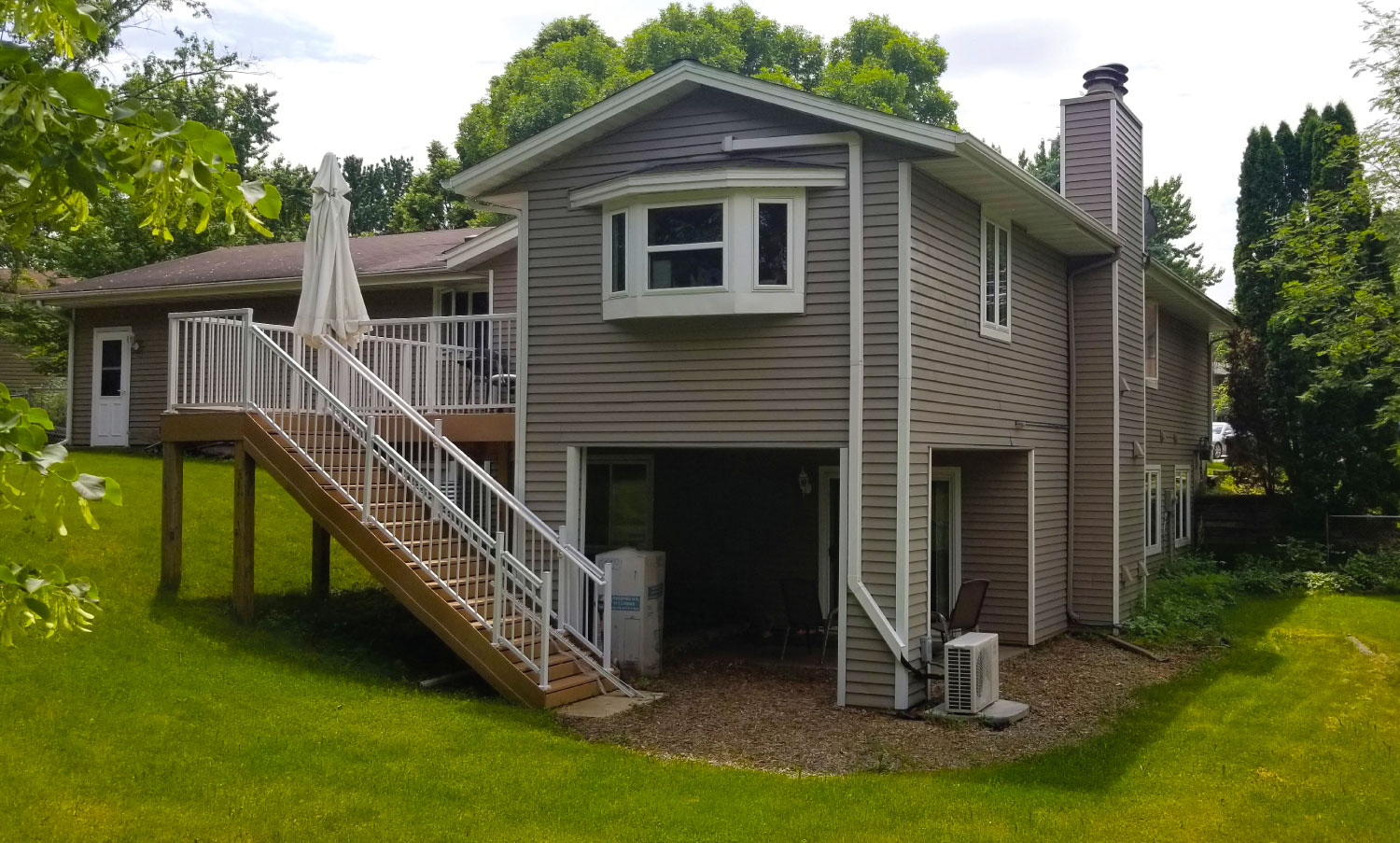 Back of home exterior with light brown siding and white trim and a deck - Maple Care Homes residential assisted living