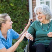 woman sitting with elderly woman in a wheelchair - Maple Care Homes Dementia Care