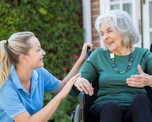 woman sitting with elderly woman in a wheelchair - Maple Care Homes Dementia Care